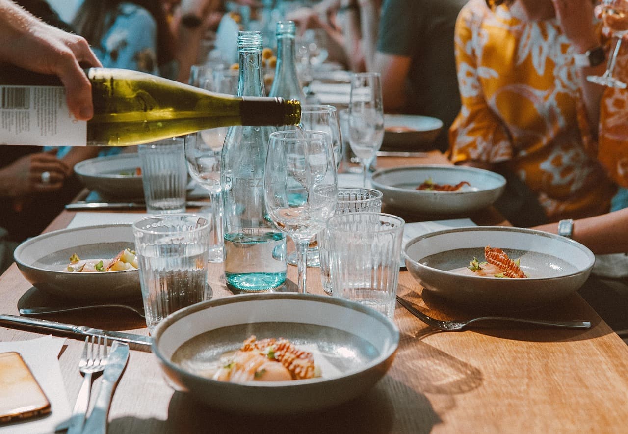 A long dinner table, wine being poured for the group